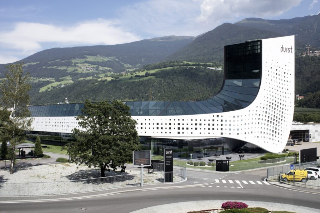 Eine pixelige weiße Welle der ikonische Hauptsitz der Durst Group AG. MPV-Design. ph Luca Gardens