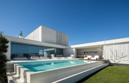 Um bloco silencioso de concreto listrado branco é a casa que se integra ao entorno através de sua serenidade